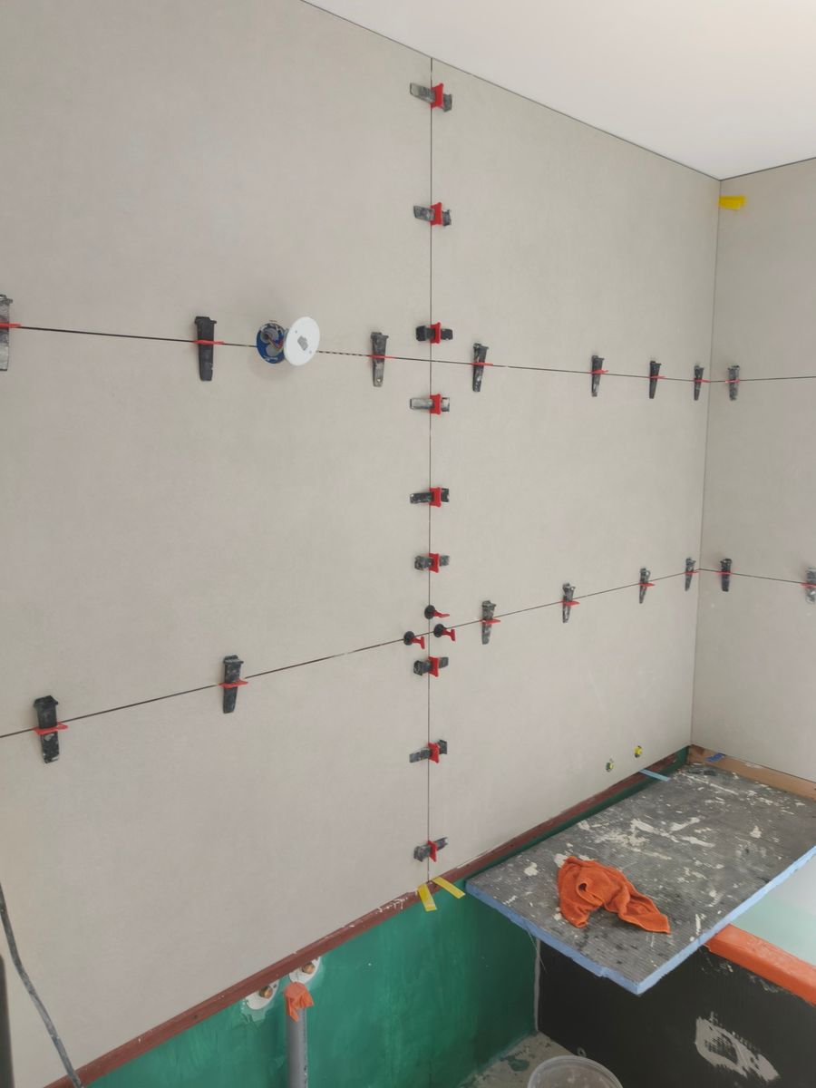 Mur de douche en grands carreaux rectifiés, clips et cales autonivelants encore en place
